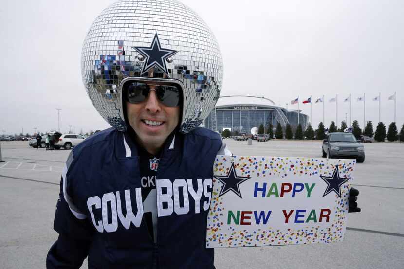 Mirrored-ball head fan Gregg Wilson holds a "HAPPY NEW YEAR" sign on the AT&T stadium...