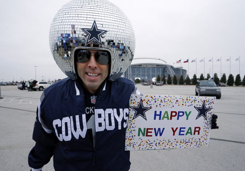 Mirrored-ball head fan Gregg Wilson holds a "HAPPY NEW YEAR" sign on the AT&T stadium...