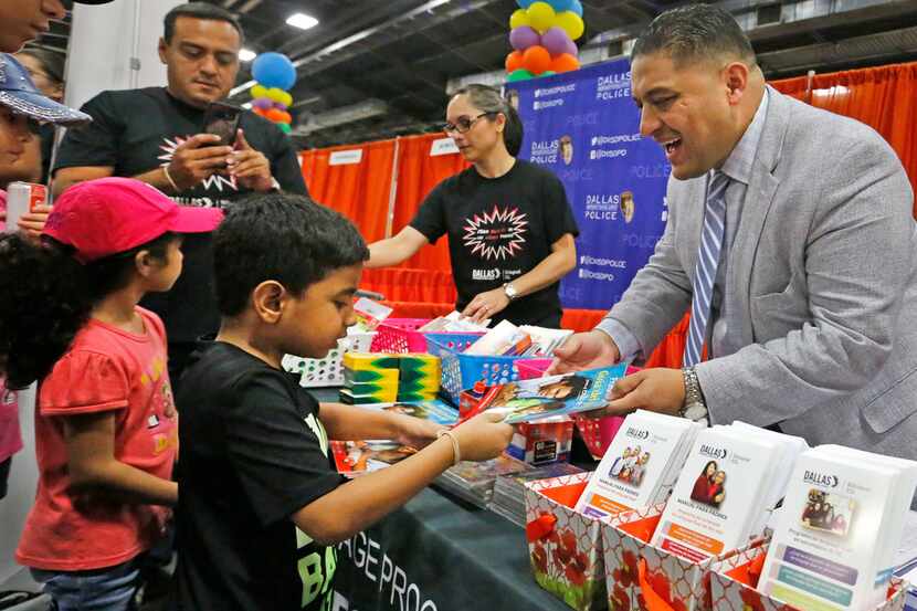 Dallas school board member Jaime Resendez hands out items to parents and students at the...