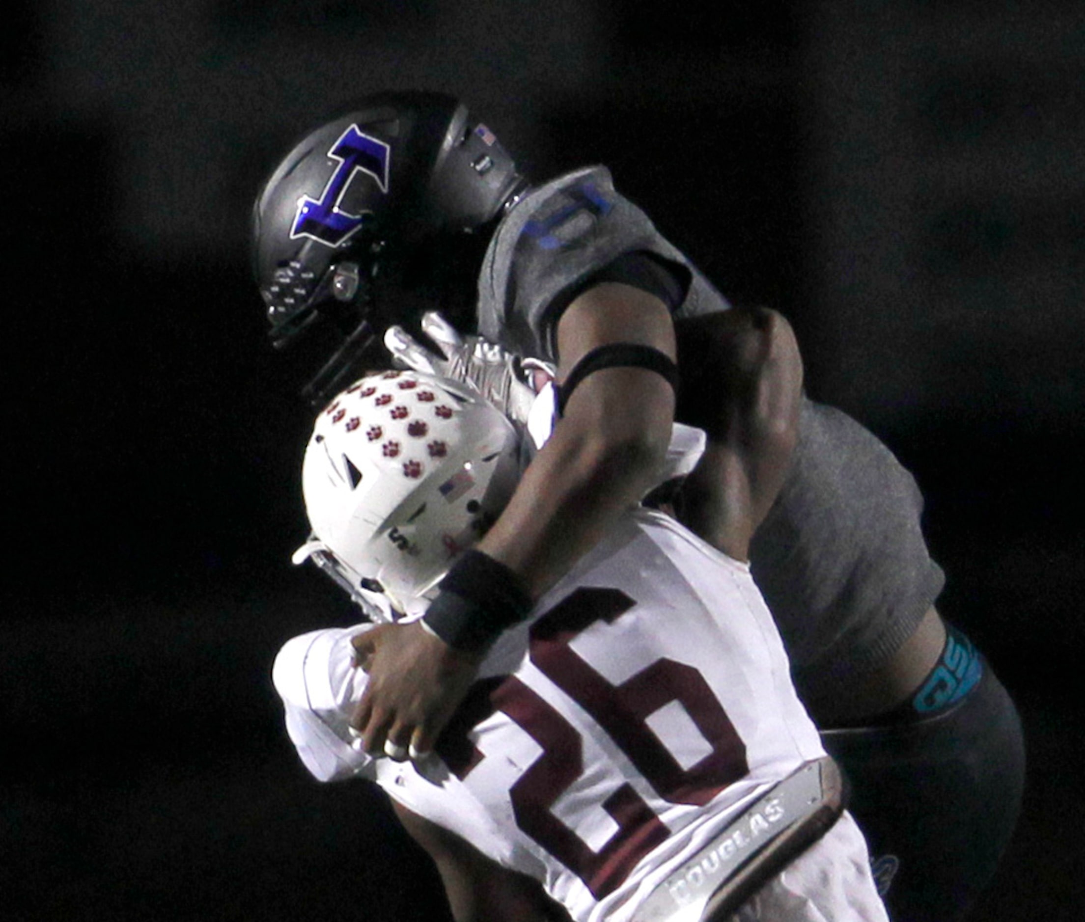 Hebron linebacker Lincoln Carrizales (20), top, stops Plano running back Kameron Jones (26)...