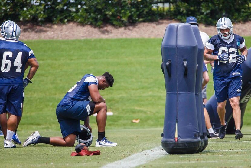 Dallas Cowboys defensive tackle David Irving (95) kneels to the side and watches teammates...