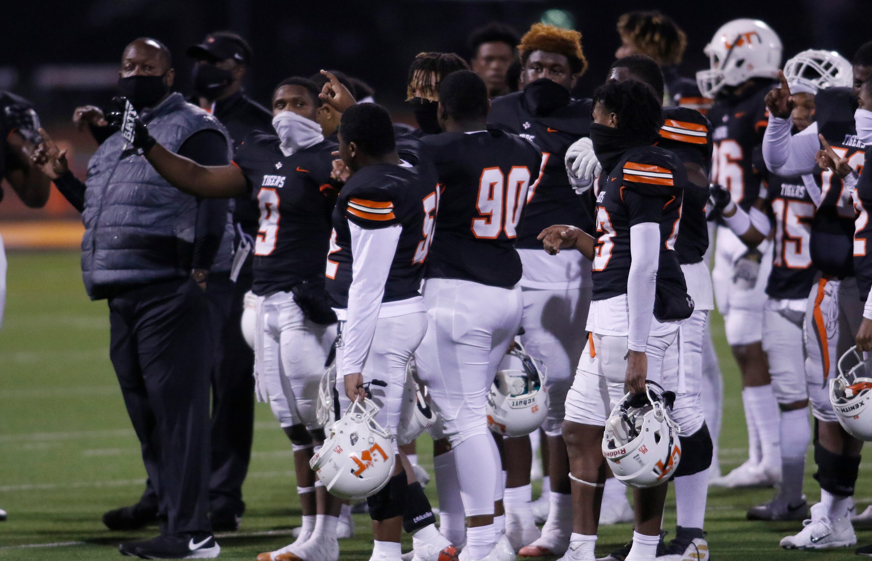 Lancaster head coach Chris Gilbert pauses with his Tigers players for the playing of their...