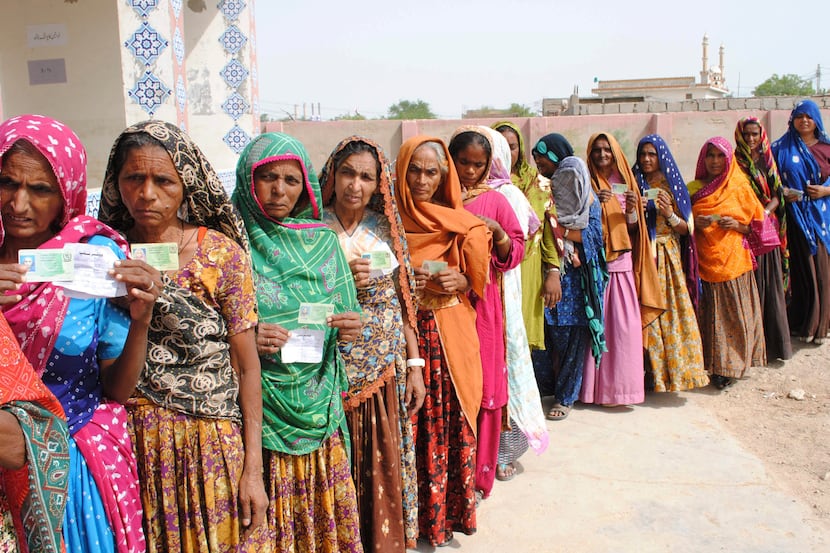 Pakistani women line up outside a polling station waiting to cast their ballots in...