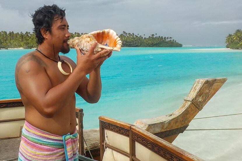 Guide Ali Maao blows a conch shell to signal the tour boat s departure from One Foot Island...