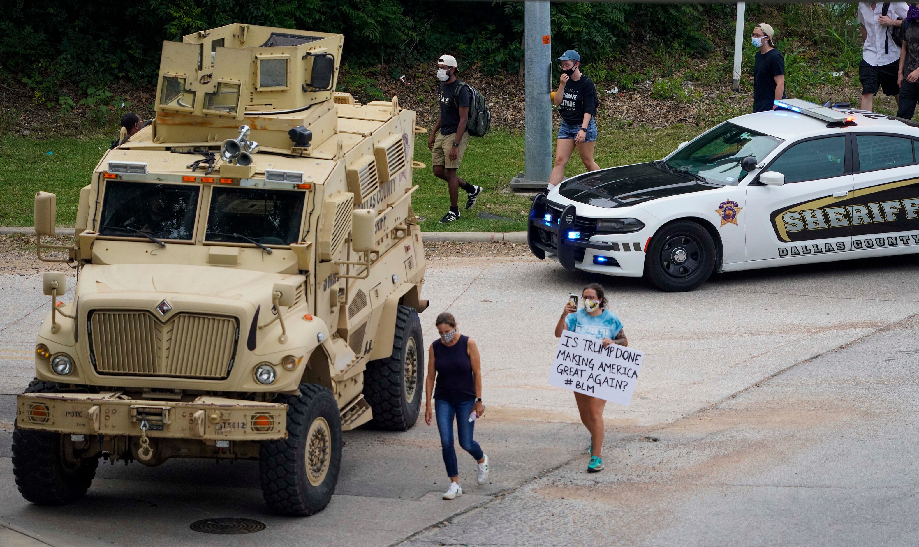 Demonstrators pass law enforcement vehicles as they head to a rally the Frank Crowley Courts...