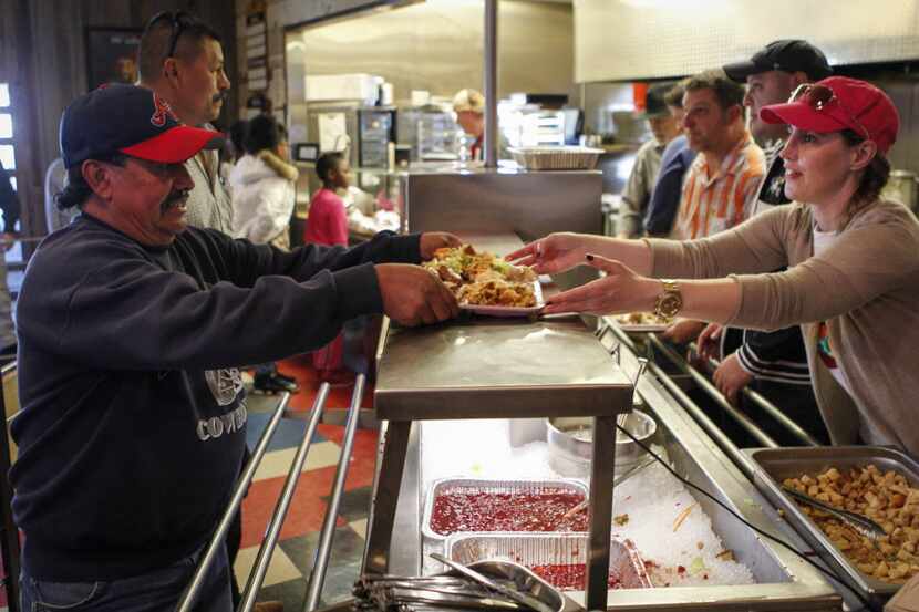Volunteer Tanya Ragan , right, serves a free Thanksgiving Day meal to Pablo Guzman, left, of...