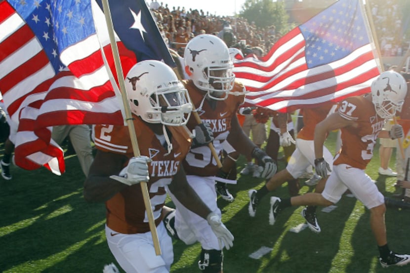 Texas players carry U.S. flags as they take the field for Saturday's game against BYU.