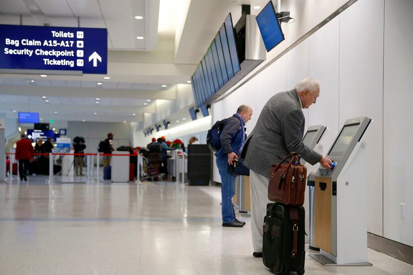  Bill Baker of Argyle uses an American Airlines self-service kiosk to check-in in Terminal A...