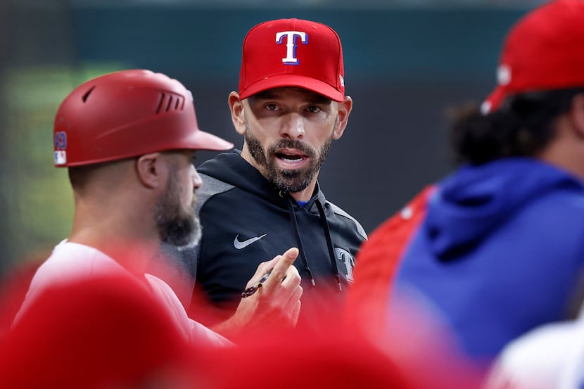 Texas Rangers manager Chris Woodward visits with first base coach Corey Ragsdale (left) in...