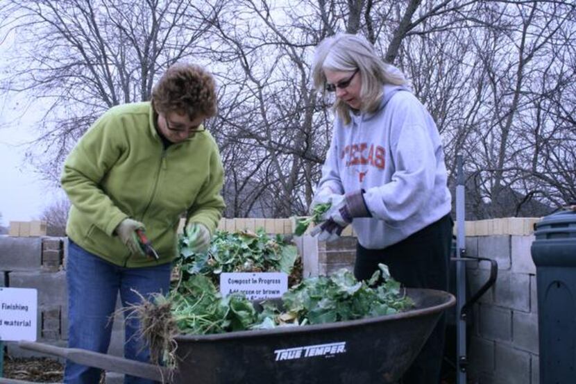 
Lisa Ingalls (left) and Terri Barrett add to The Giving Garden’s compost pile. 
