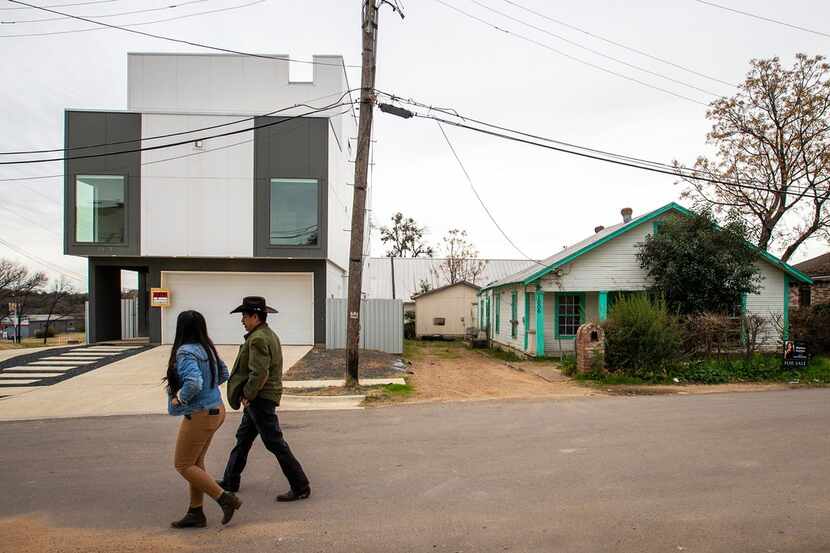Elizabeth Garcia and her father, Leonardo Garcia, walk past both new and old homes in their...