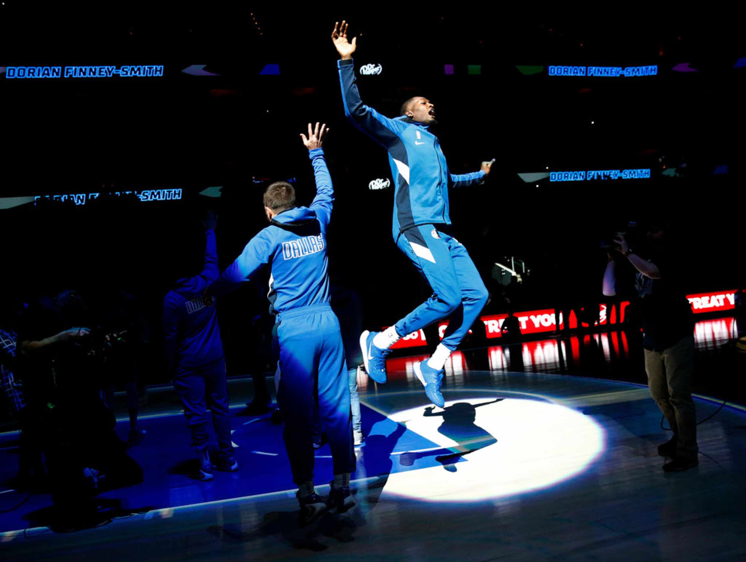 Dallas Mavericks forward Dorian Finney-Smith leaps in the air as he's welcomed by guard J.J....
