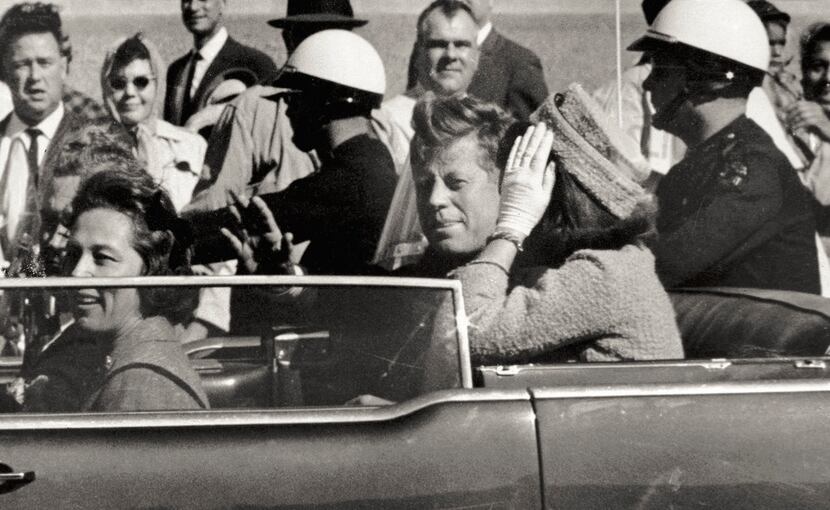President John F. Kennedy waved from his car in a motorcade approximately one minute before...