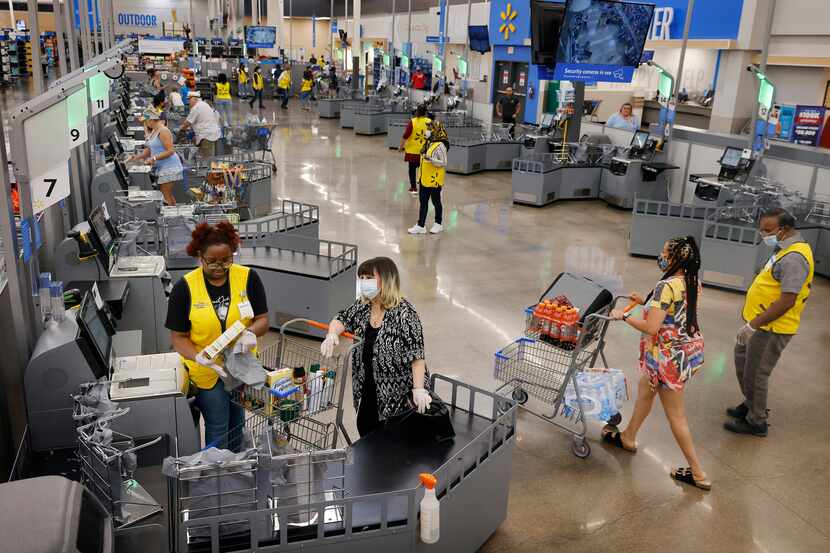 Associates dressed in yellow vests assist customers at the new self checkout corral inside ...