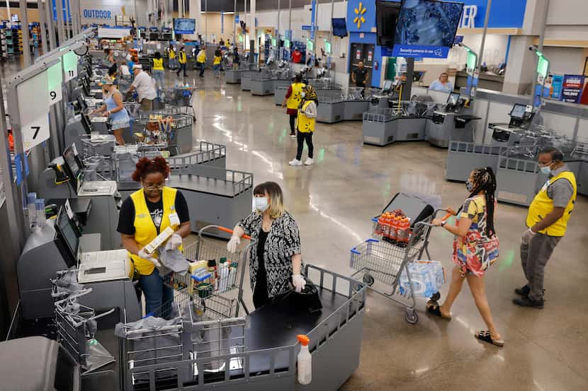 Associates dressed in yellow vests assist customers at the new self checkout corral inside ...