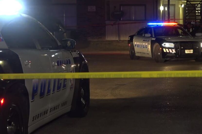 Dallas police squad cars sit parked outside an apartment complex where a man suspected in...