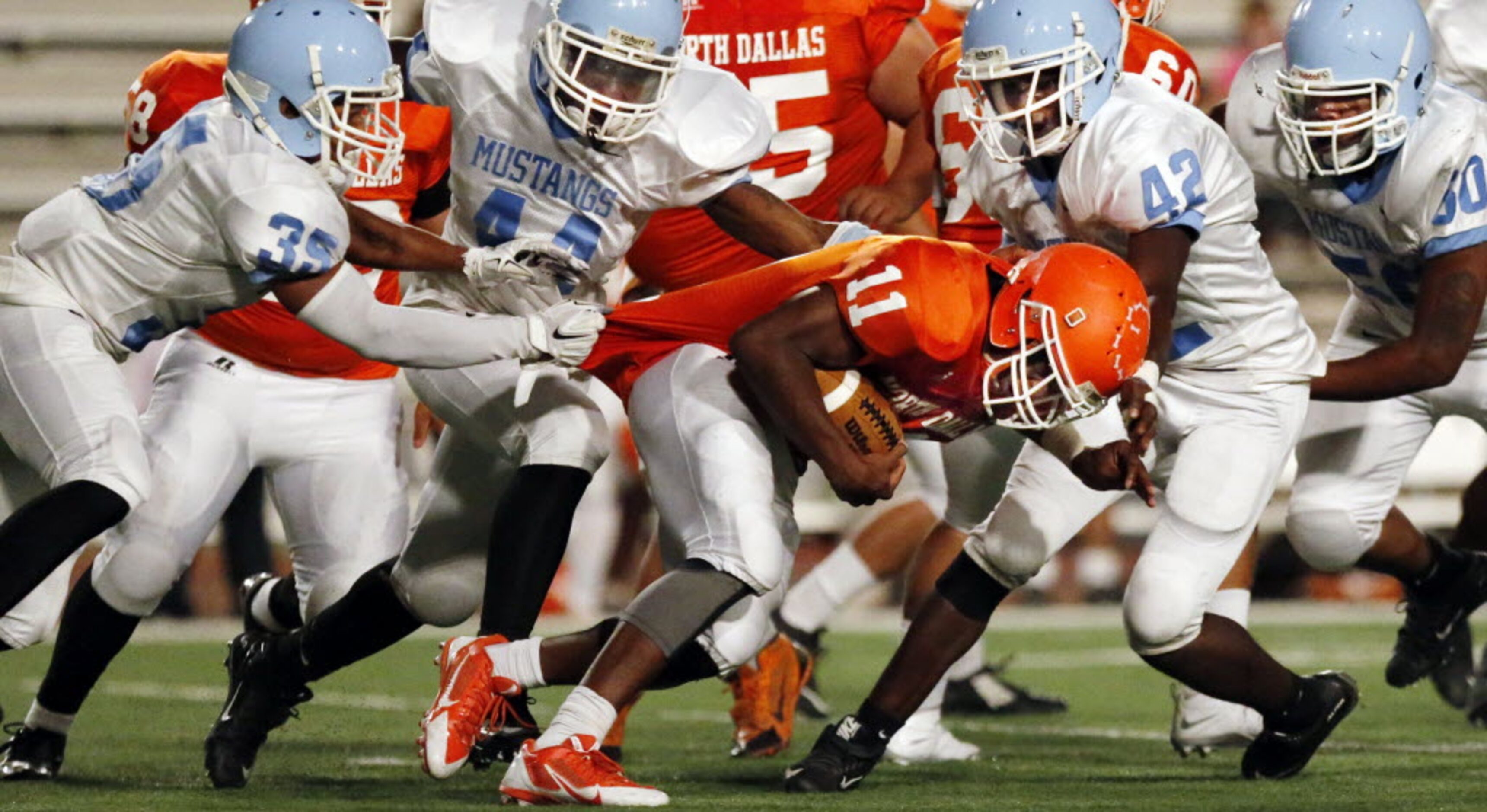 (TXHSFB) North Dallas RB Geovani Manning (11) grinds out a couple of yards, as a swarm of...