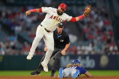 Los Angeles Angels shortstop Luis Guillorme, left, is unable to tag out Texas Rangers...