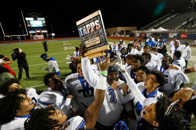 Trinity Christian's head coach Andre' Hart celebrates with the team as he passes the trophy...