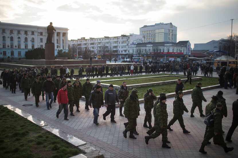 Pro-Russian self-defense force volunteers march past a statue of Lenin in Simferopol,...