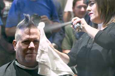 Stylist Vicky Peña sprays temporary hair dye on George Dunham's hair at Boardroom Salon for...