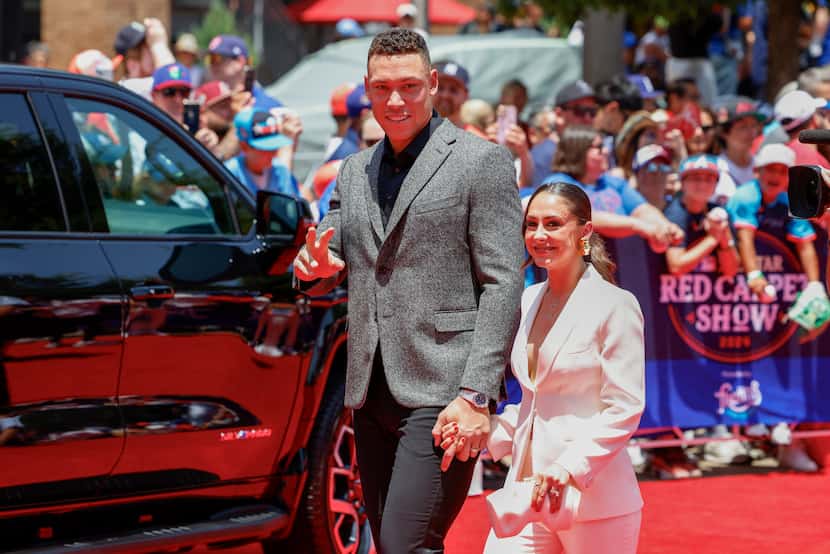 New York Yankees outfielder Aaron Judge waves to fans as he walks with his wife Samantha...