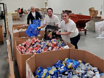 Fannie Mae employees volunteer at the North Texas Food Bank and are sorting cans of food...