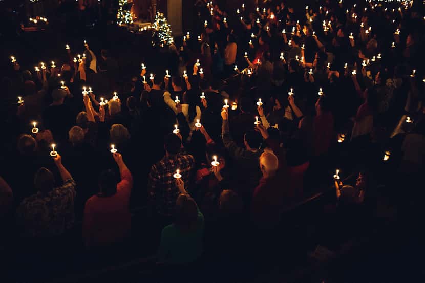Members of a church congregation hold lighted candles aloft during a time of celebration on...