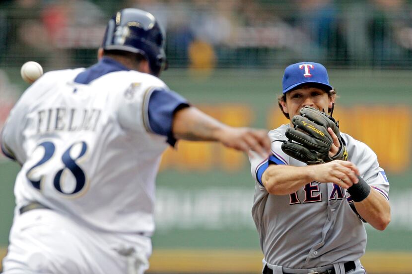 Texas Rangers second baseman Ian Kinsler, right, throws the ball past Milwaukee Brewers'...