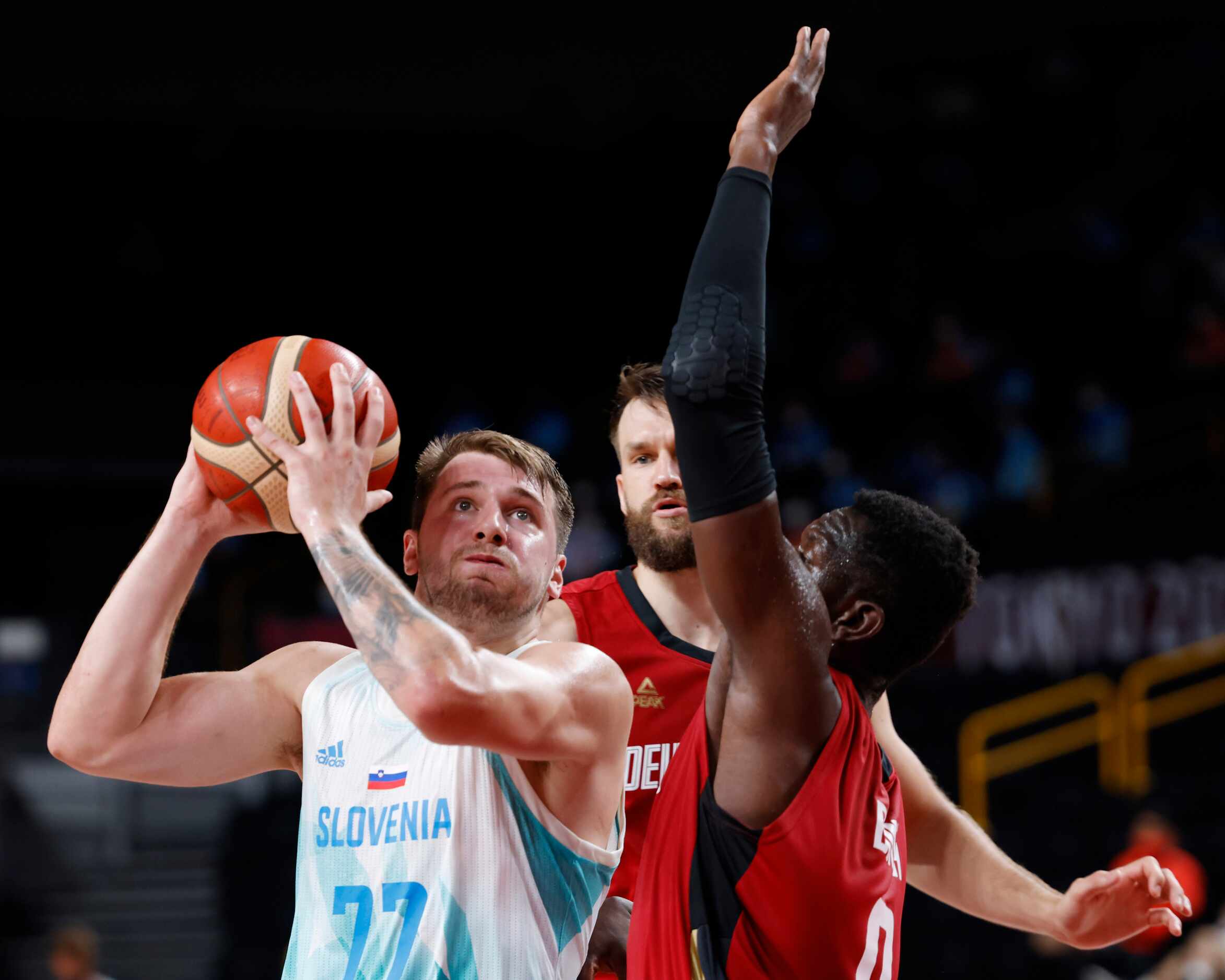 Slovenia’s Luka Doncic (77) drives in between Germany’s Danilo Barthel (22) and Isaac Bonga...