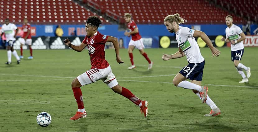 Jonathan Gomez rushes upfield with Greenville's Evan Lee in pursuit in the USL League One...