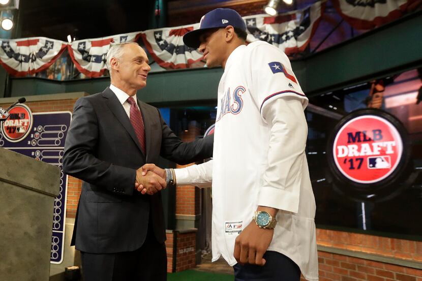 Baseball commissioner Rob Manfred, left, shakes hands with Bubba Thompson, an outfielder...