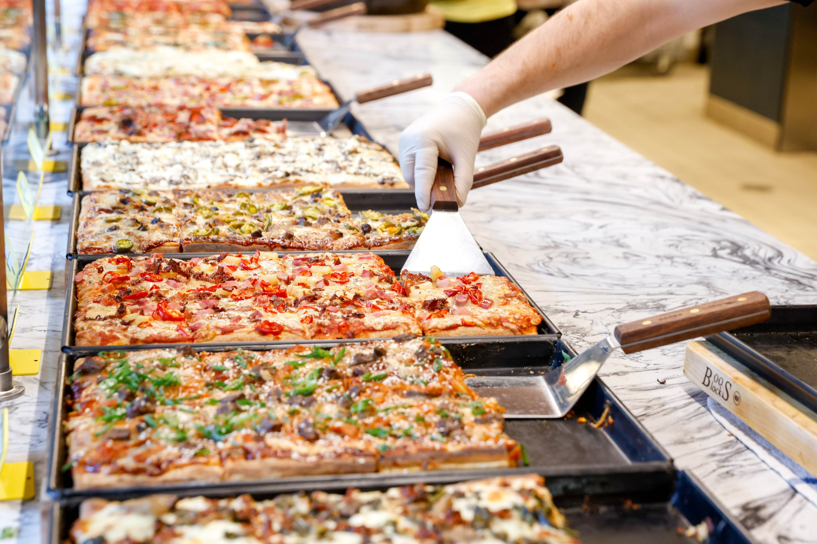 Mario Rios serves a slice of pizza at Pizza Leila in Dallas on Monday, March 20, 2023.