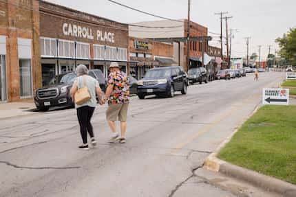 A car stops for a couple crossing Main Street, which is also State Highway 352, as they head...