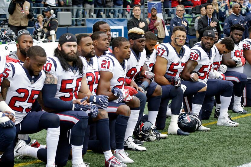 Houston Texans players kneel during the singing of the national anthem before an NFL...