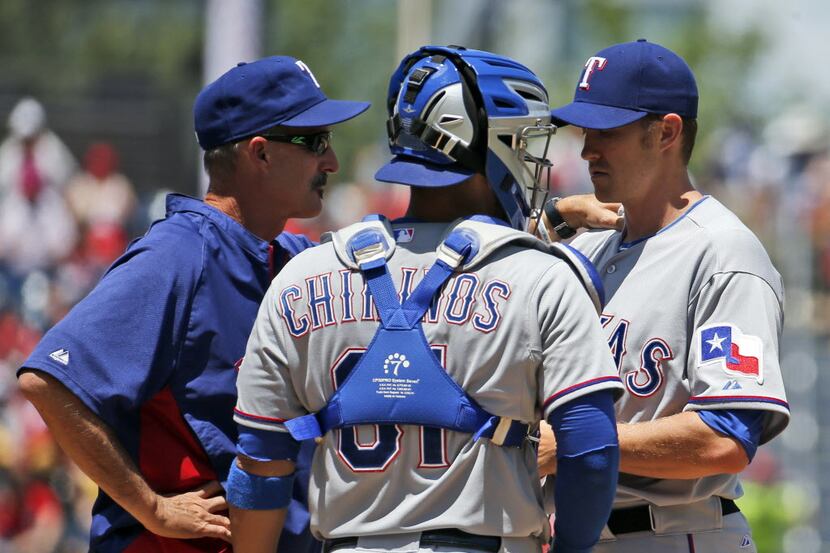 Texas Rangers pitching coach Mike Maddux, left, talks with catcher Robinson Chirinos, and...