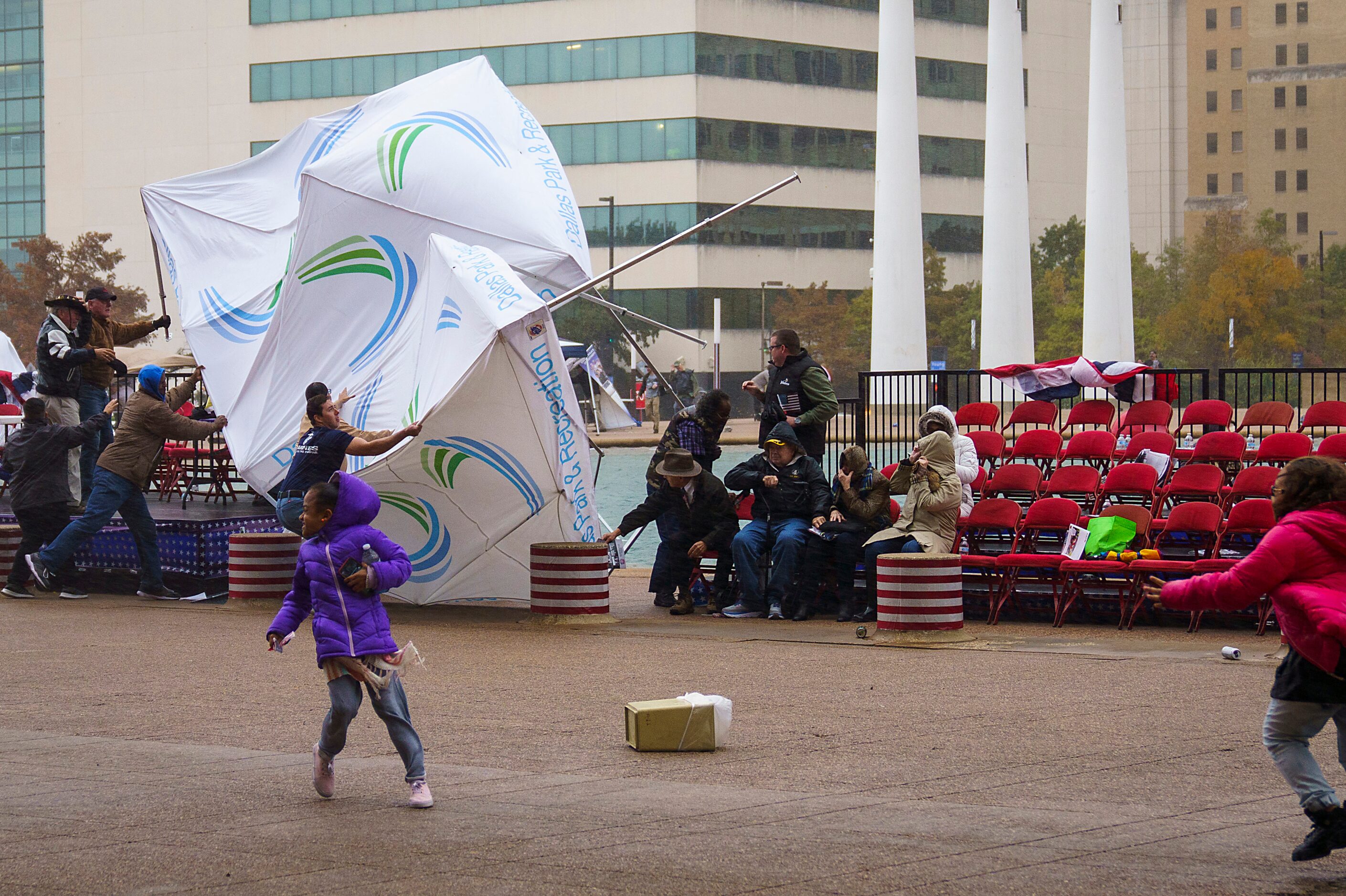 Spectators run for cover as a strong wind turns over a Dallas Parks and Recreation...