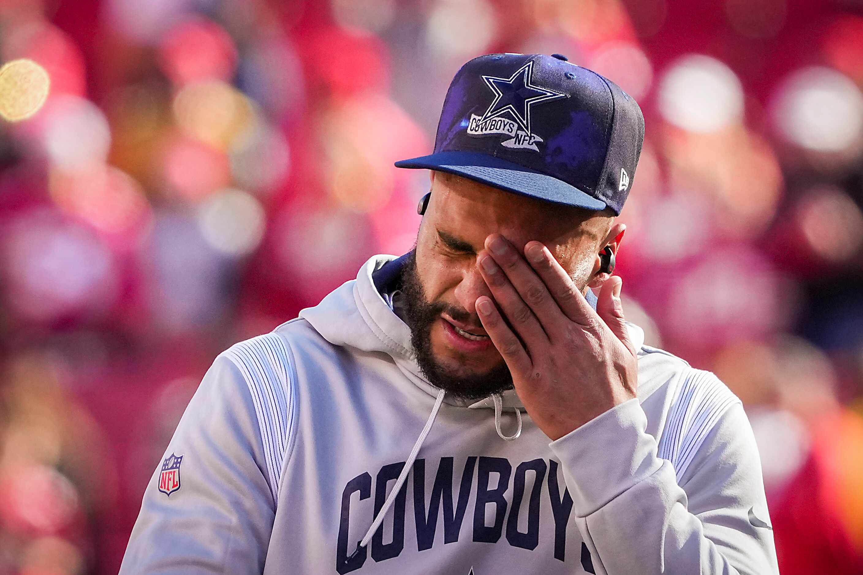 Dallas Cowboys quarterback Dak Prescott wipes his eyes as he warms up before an NFL...
