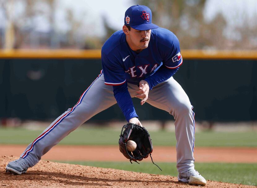 Texas Rangers pitcher Cole Ragans fields a ball during a spring training workout at the...
