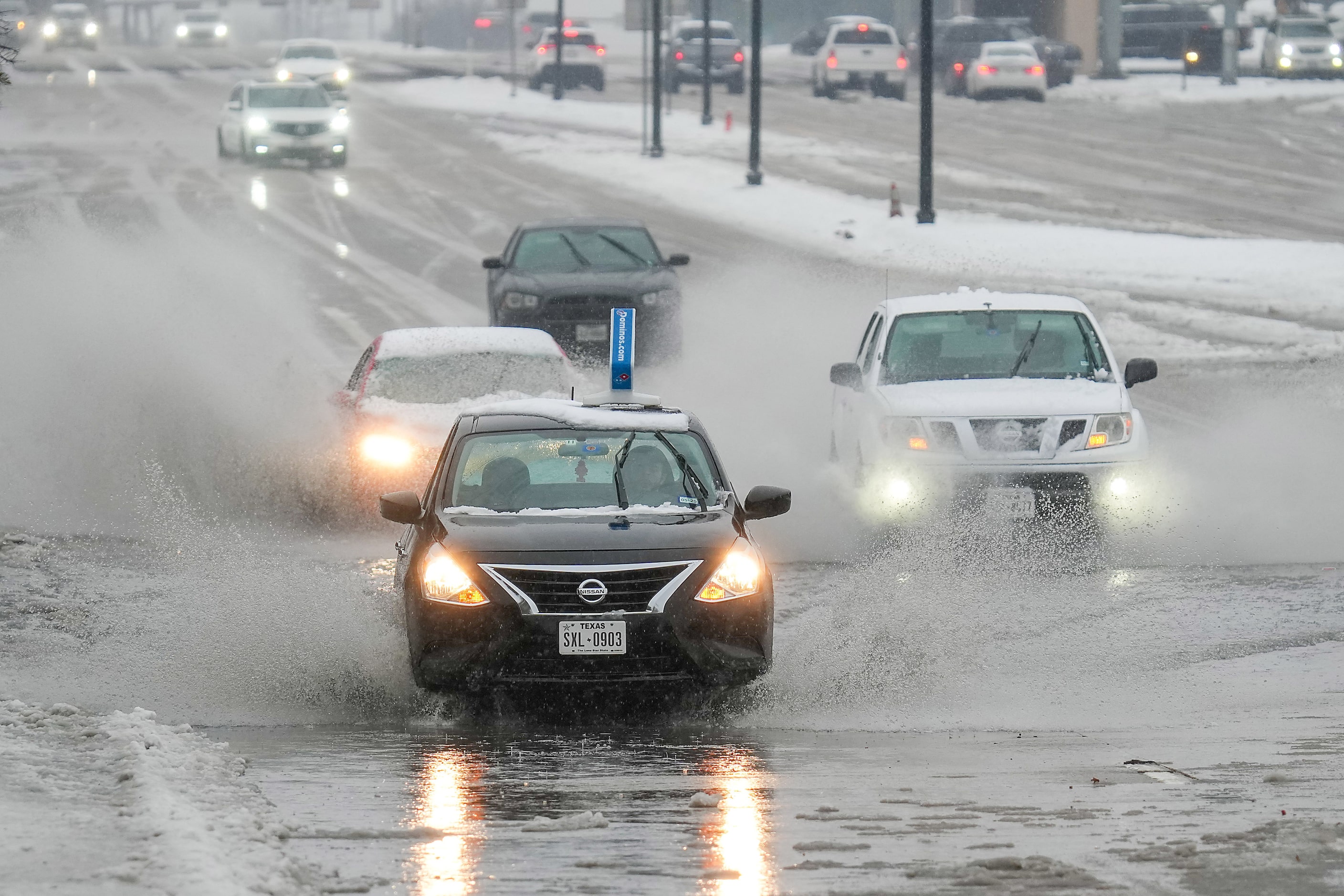 Motorists drive through standing water on University Drive after snow turned to rain on...