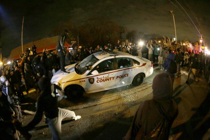  A protester squirts lighter fluid on a police car as the car windows are shuttered near the...