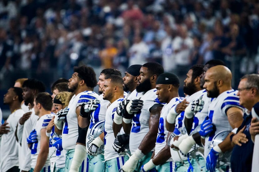 The Dallas Cowboys stand during the national anthem before their opener against the New York...