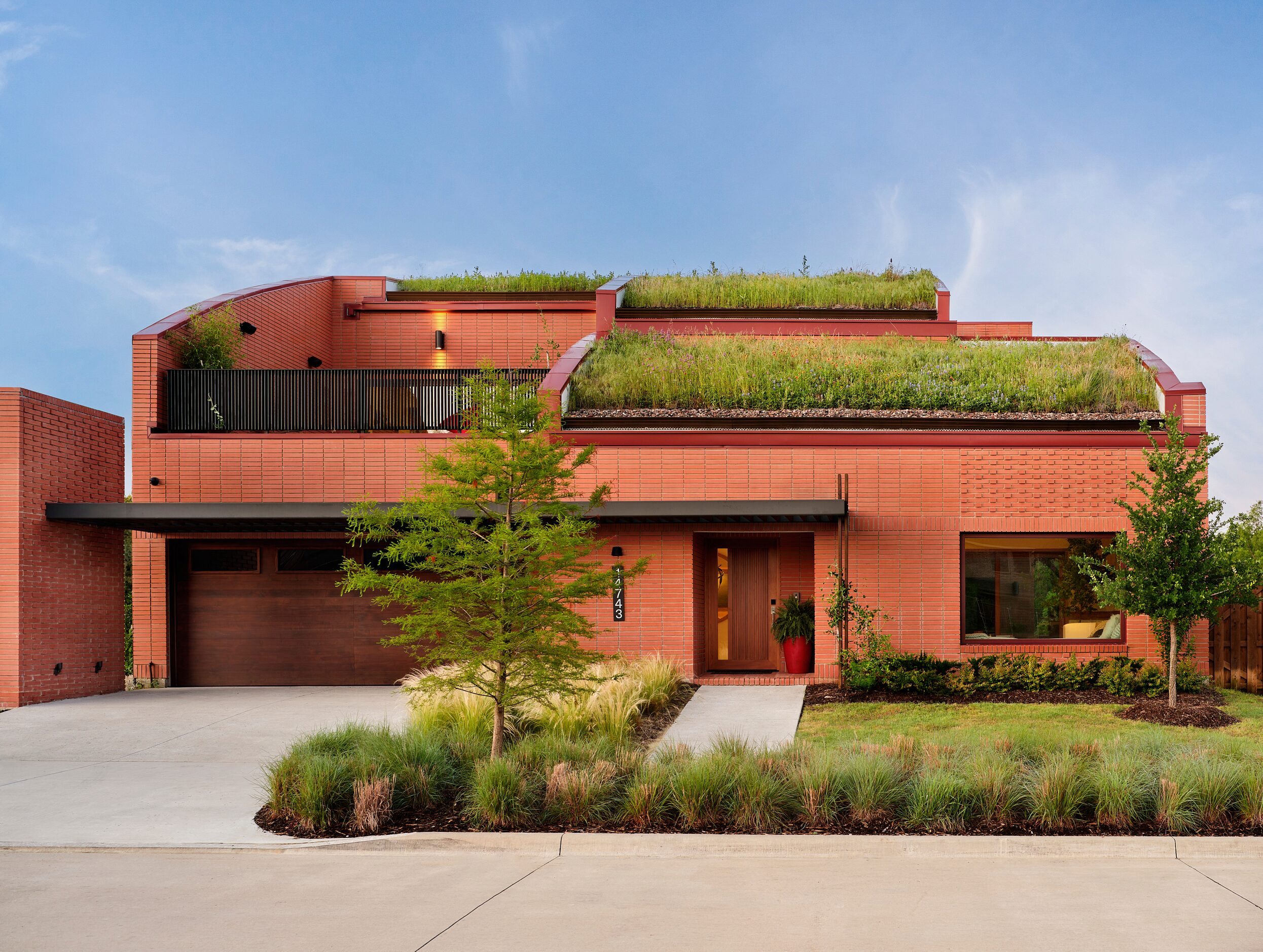 Red, terra-cotta colored house exterior with grass on roof