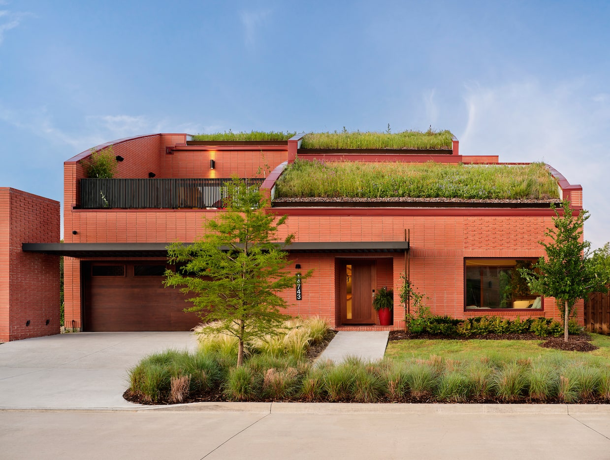 Red, terra-cotta colored house exterior with grass on roof