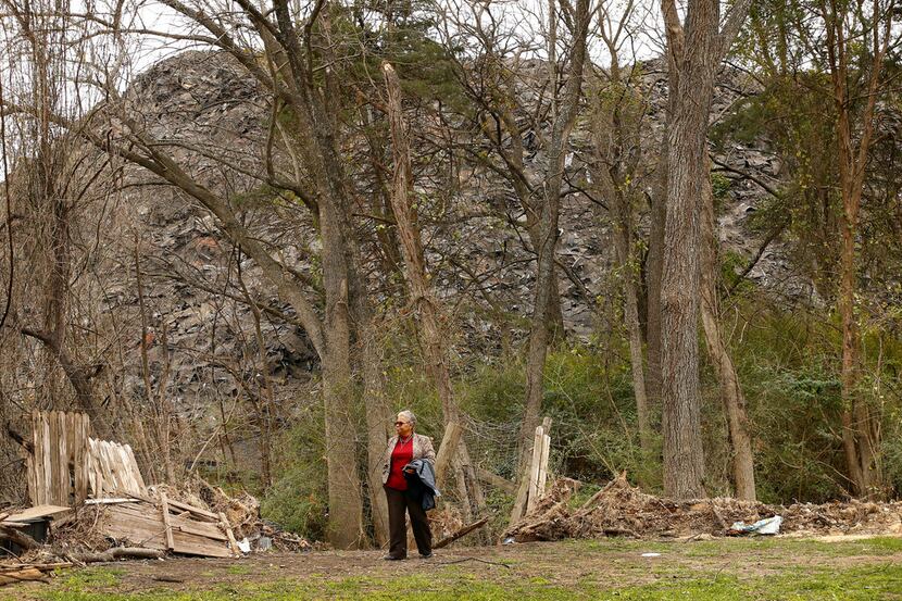Homeowner Marsha Jackson walks past her flood-damaged fencing bordering a large hill of...