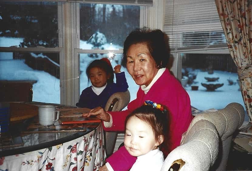 My older sister Michele (left) and I (right) sit around my grandmother in the kitchen of her...