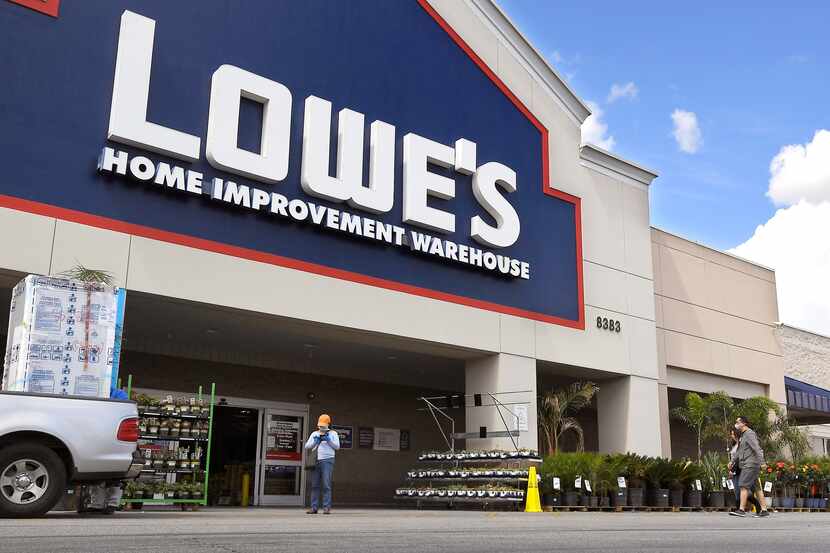 In this March 22, 2020 file photo, customers wearing masks walk into a Lowe's home...