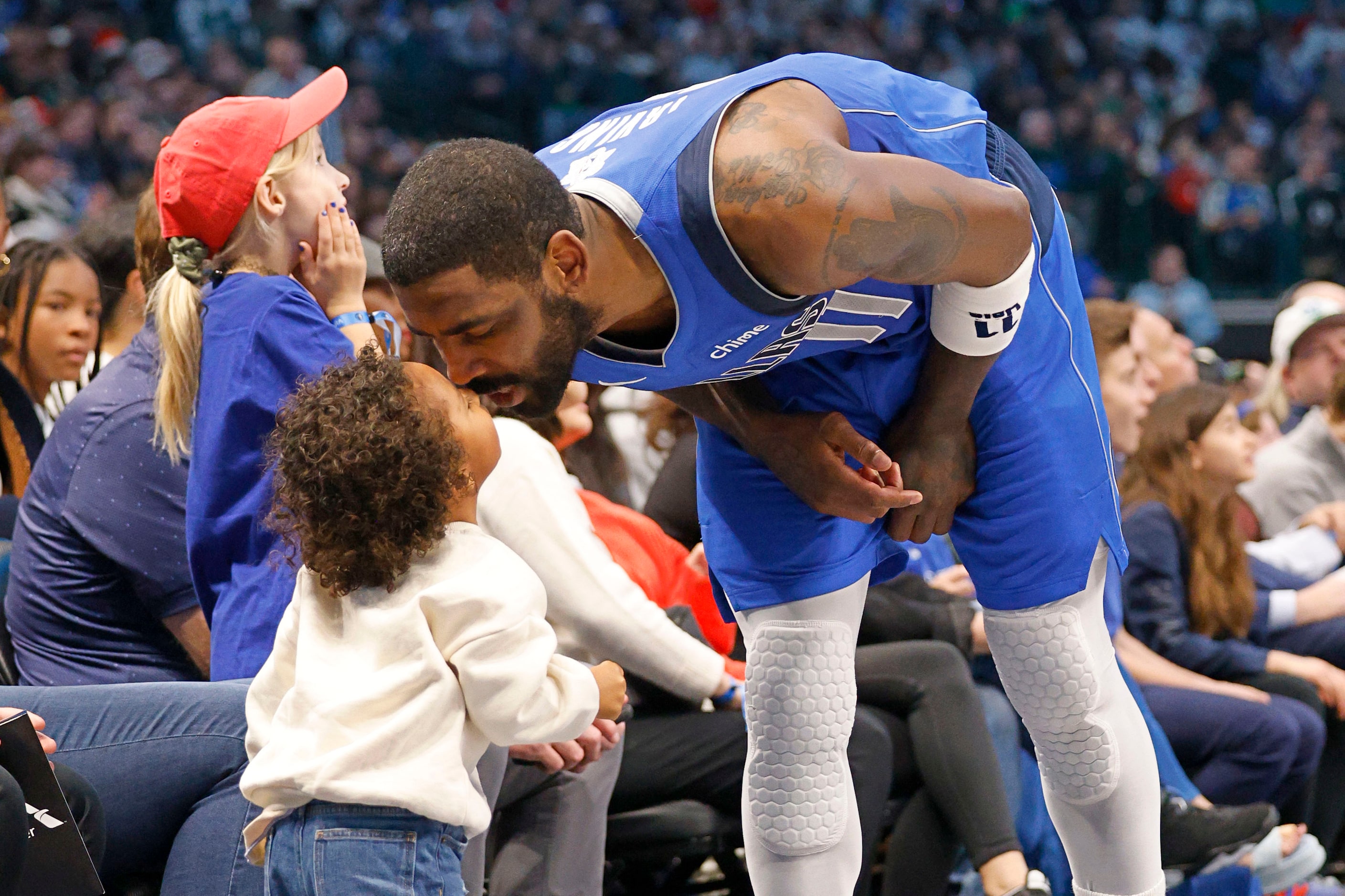 Dallas Mavericks guard Kyrie Irving (11) kisses his child during a timeout in the first half...