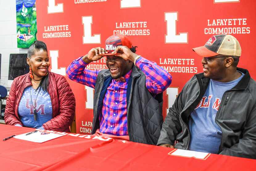 Lafayette High linebacker Eric Jeffries, center, puts on an Ole Miss cap after signing to...