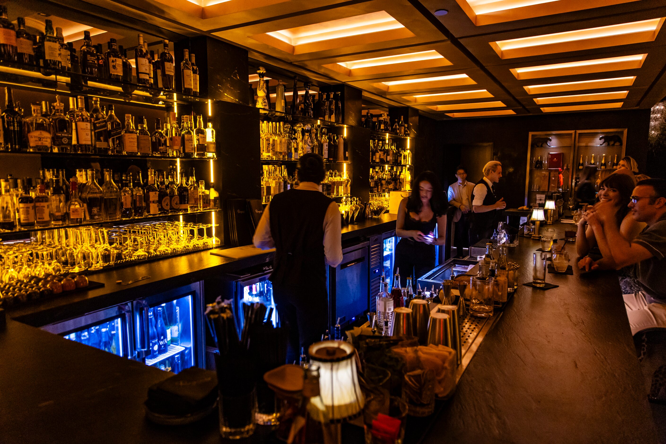 The bar at Regines in Dallas is backlit with gold.